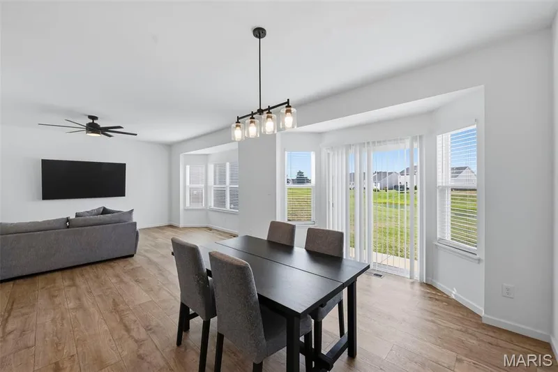 Wood-finish flooring, bay window, sliding glass door, modern linear chandelier, and ceiling fan — 191 Crestfield Court, St Charles, MO 63301