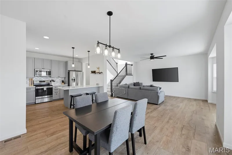 Open-concept living space featuring wood-finish flooring, a contemporary kitchen with stainless steel appliances, and a central island with bar seating — 191 Crestfield Court, St Charles, MO 63301