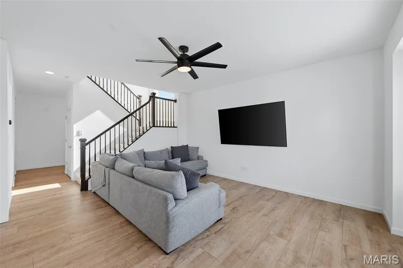 Wood-finish flooring, staircase with black spindles, ceiling fan with integrated lighting, recessed lighting, and white walls — 191 Crestfield Court, St Charles, MO 63301