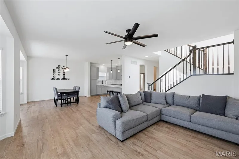 Open-concept living area featuring wood-finish flooring and a black ceiling fan — 191 Crestfield Court, St Charles, MO 63301