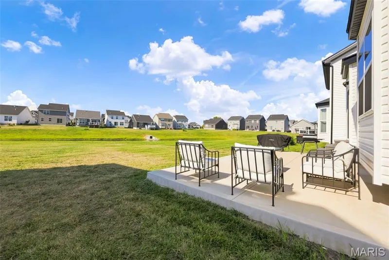 Concrete patio with ample space for outdoor furniture, featuring a wide expanse of green lawn — 191 Crestfield Court, St Charles, MO 63301