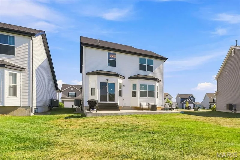 Expansive backyard featuring a large concrete patio, sliding glass doors, and multiple bay windows — 191 Crestfield Court, St Charles, MO 63301