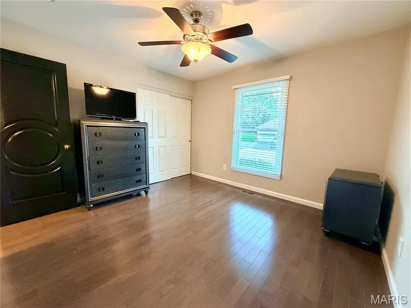 Wood-finish flooring, ceiling fan with integrated lighting, window with blinds, and a paneled closet door — 584 Sunbridge Drive, Chesterfield, MO 63017