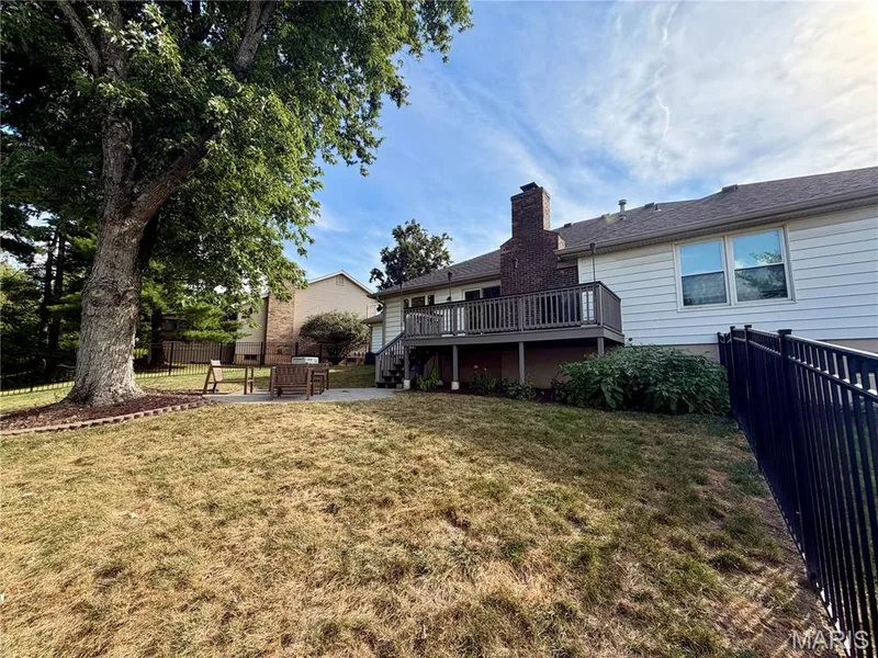 Expansive backyard featuring a mature tree, stone patio, and a two-story wood deck — 584 Sunbridge Drive, Chesterfield, MO 63017