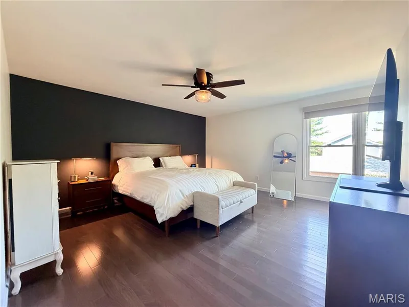 Hardwood flooring, ceiling fan with integrated lighting, expansive window with roller shade, and an accent wall — 584 Sunbridge Drive, Chesterfield, MO 63017