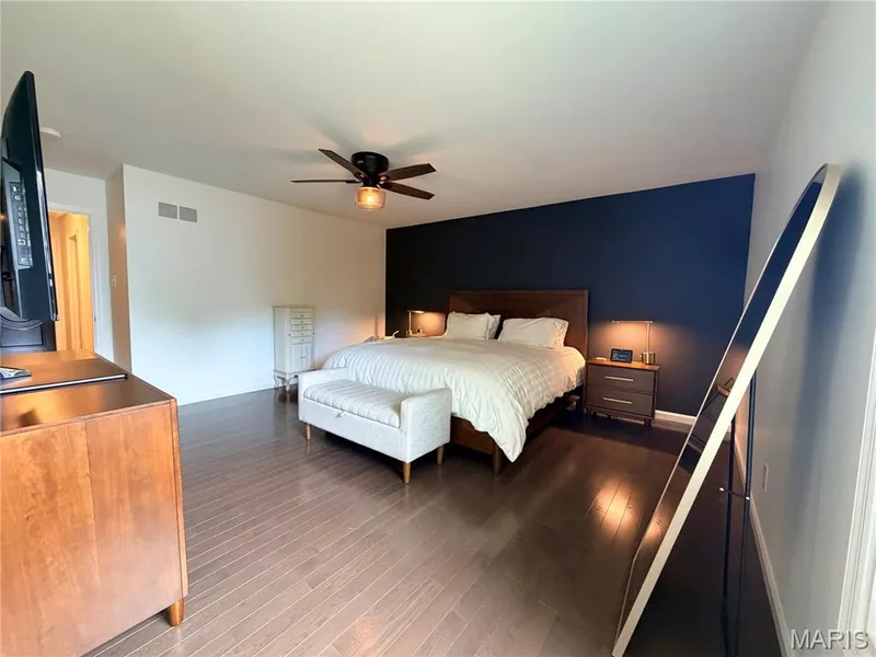 Wood-finish flooring, accent wall, ceiling fan with integrated lighting, recessed lighting, and a wood-finish bed frame — 584 Sunbridge Drive, Chesterfield, MO 63017