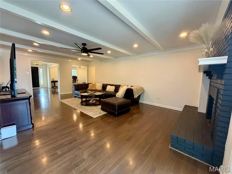 Hardwood flooring, painted brick fireplace with mantel, recessed lighting, exposed ceiling beams, and a ceiling fan — 584 Sunbridge Drive, Chesterfield, MO 63017