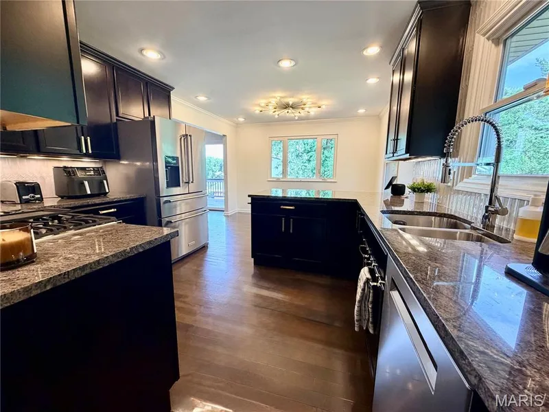 Kitchen featuring dark wood cabinetry, stainless steel appliances, granite countertops, and wood-finish flooring — 584 Sunbridge Drive, Chesterfield, MO 63017