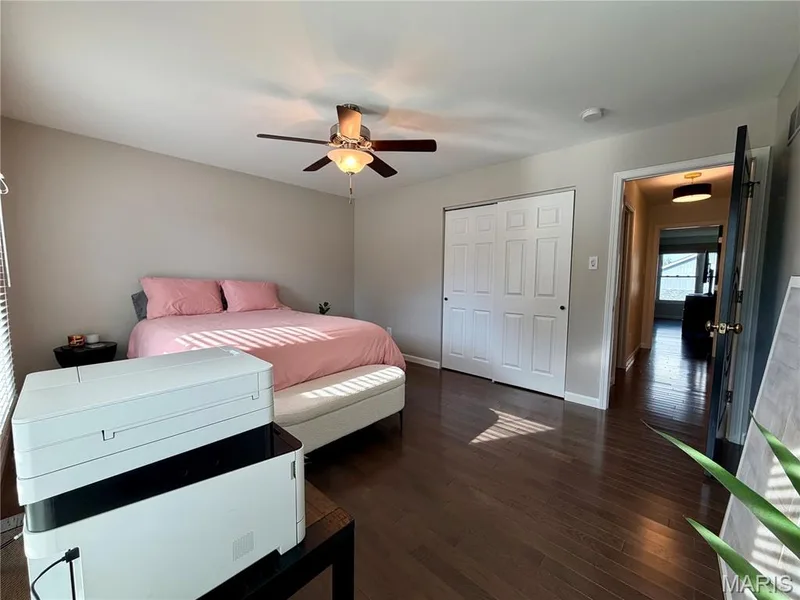 Wood-finish flooring, ceiling fan with integrated lighting, neutral wall paint, and white bi-fold closet doors — 584 Sunbridge Drive, Chesterfield, MO 63017