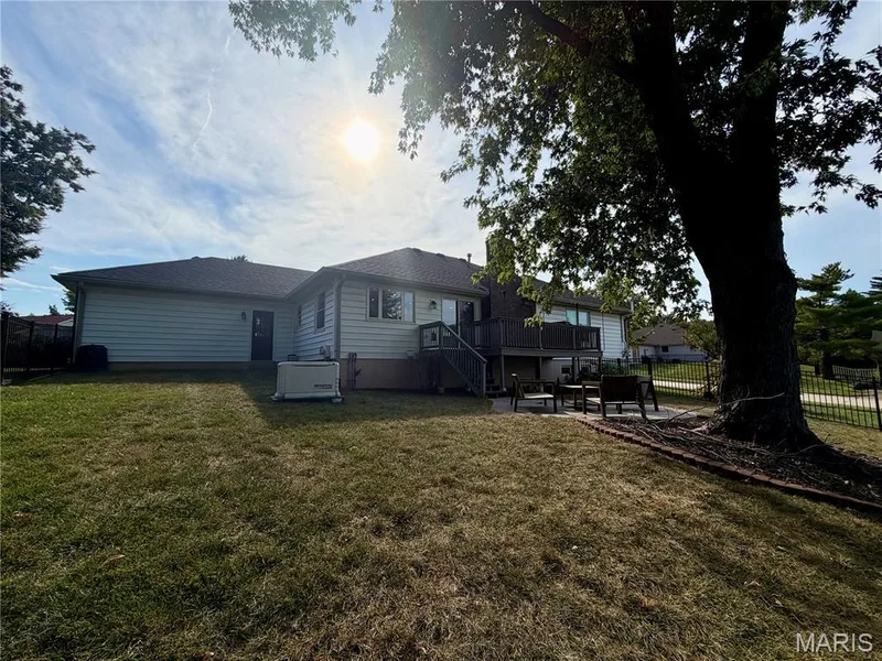 Expansive backyard with a large shade tree, tiered deck, and a patio area — 584 Sunbridge Drive, Chesterfield, MO 63017