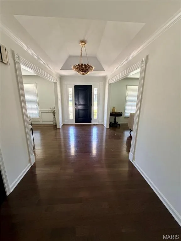Foyer with wood-finish flooring, a tray ceiling, and a decorative chandelier — 584 Sunbridge Drive, Chesterfield, MO 63017