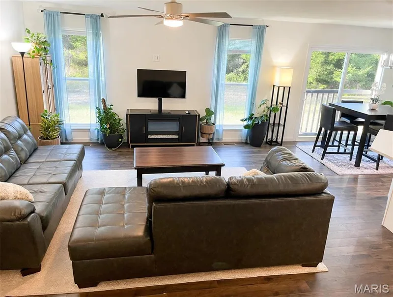 Vaulted ceiling with ceiling fan, wood-finish flooring, multiple large windows, and sliding glass door with deck access — 157 Day Lily Lane, Wentzville, MO 63385