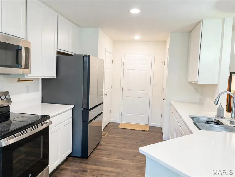 White cabinetry, white countertops, stainless steel appliances, wood-finish flooring, recessed lighting — 157 Day Lily Lane, Wentzville, MO 63385