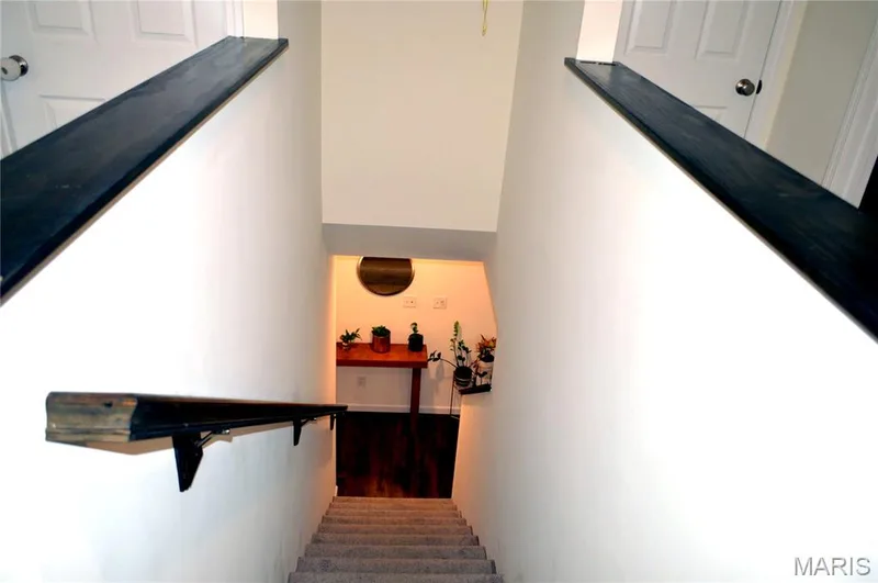 Carpeted staircase featuring a dark wood-finish handrail — 157 Day Lily Lane, Wentzville, MO 63385