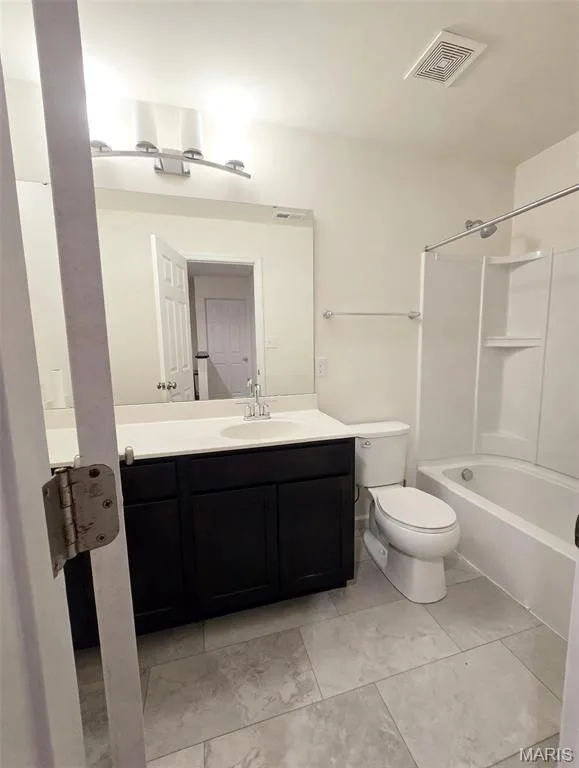 Bathroom featuring a dark wood-finish vanity with a white countertop, large mirror, and tiled flooring — 157 Day Lily Lane, Wentzville, MO 63385