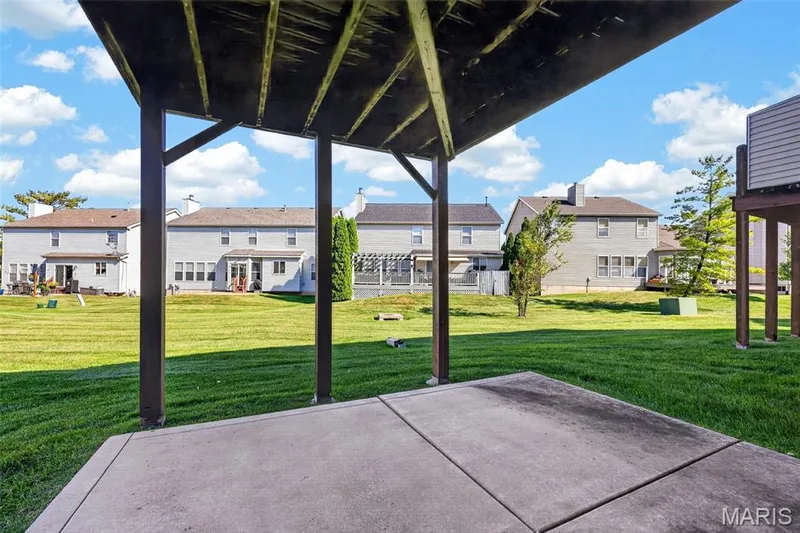 Paved patio area beneath a structural deck, featuring a vast grassy yard — 29 Edenshire Court #69B, Dardenne Prairie, MO 63368