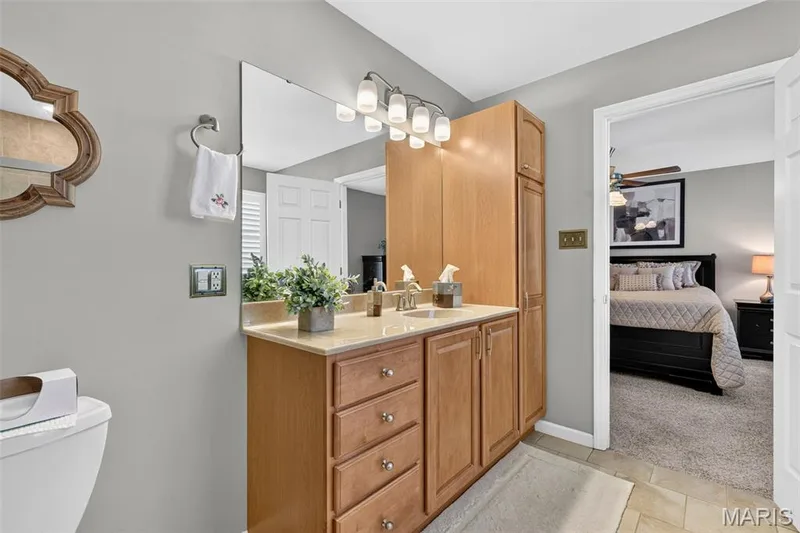 Bathroom vanity with light wood cabinetry, a light-colored countertop, and a built-in sink — 29 Edenshire Court #69B, Dardenne Prairie, MO 63368