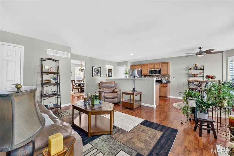 Hardwood flooring throughout, kitchen with wood-finish cabinetry, stainless steel appliances, and ceiling fan with integrated lighting — 29 Edenshire Court #69B, Dardenne Prairie, MO 63368