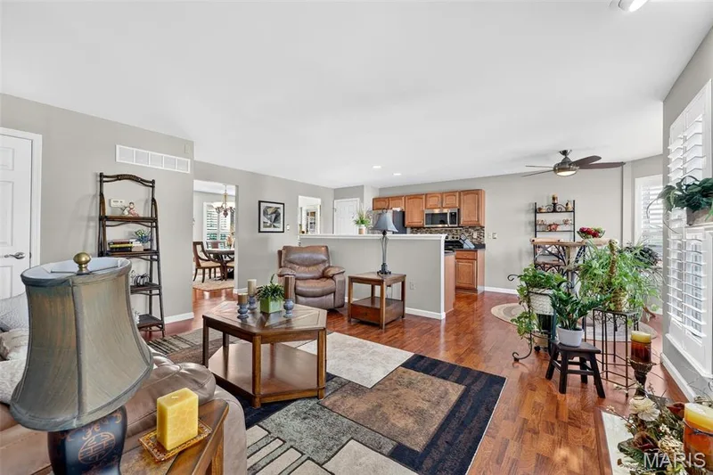 Wood-finish flooring throughout, ceiling fan with integrated lighting, kitchen featuring wood cabinetry and stainless-steel appliances, and plantation shutters — 29 Edenshire Court #69B, Dardenne Prairie, MO 63368