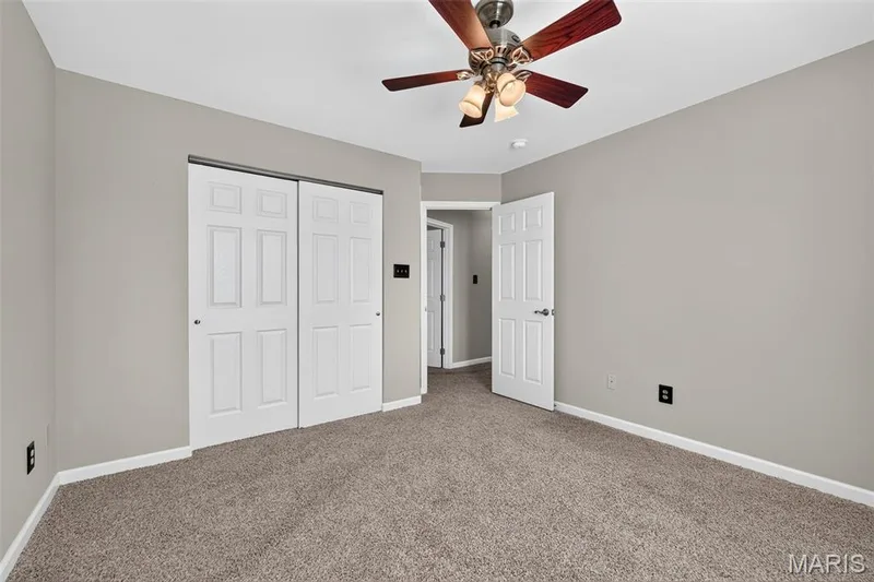 Neutral wall paint, plush carpeting, ceiling fan with integrated lighting, bi-fold closet doors, and white paneled doors — 29 Edenshire Court #69B, Dardenne Prairie, MO 63368