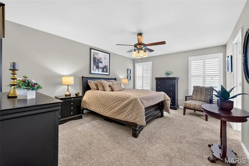 Vaulted ceiling, two windows with plantation shutters, ceiling fan with integrated lighting, and neutral carpeting — 29 Edenshire Court #69B, Dardenne Prairie, MO 63368
