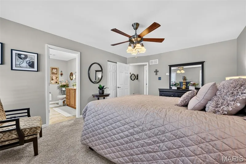 Carpeted flooring, ceiling fan with light fixture, light gray wall paint, white trim, and a built-in wood vanity with a white countertop in the bathroom — 29 Edenshire Court #69B, Dardenne Prairie, MO 63368