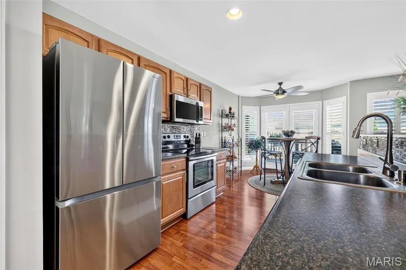 Kitchen featuring wood-finish flooring, stainless steel appliances, and wood cabinetry — 29 Edenshire Court #69B, Dardenne Prairie, MO 63368