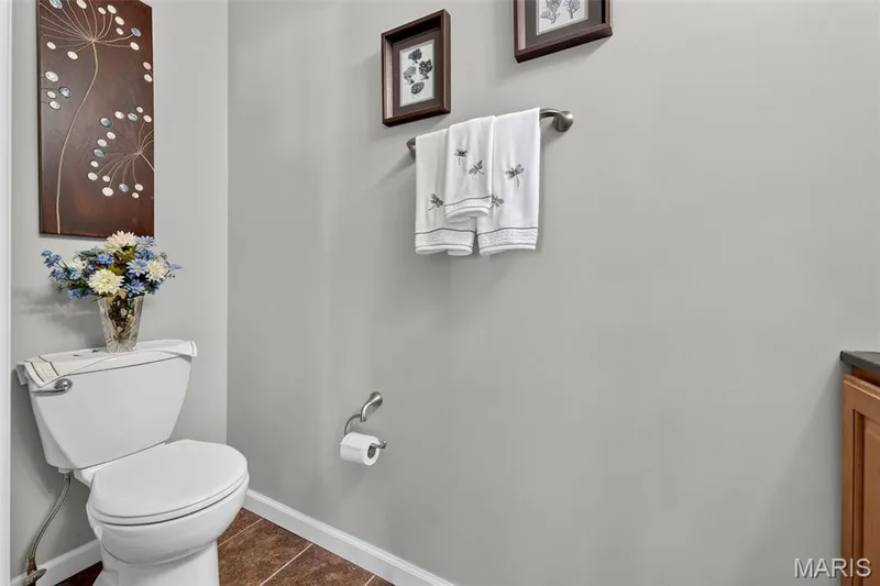 Porcelain toilet with tile flooring, wood-finish vanity with dark countertop, and wall-mounted towel bar — 29 Edenshire Court #69B, Dardenne Prairie, MO 63368