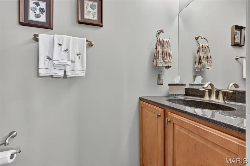 Built-in vanity with wood-finish cabinetry, dark granite countertop, and undermount sink — 29 Edenshire Court #69B, Dardenne Prairie, MO 63368