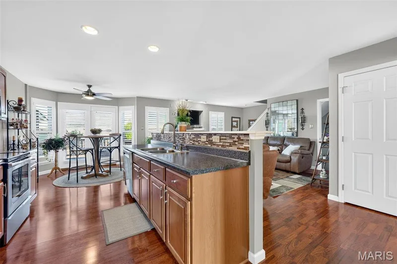 Wood-finish flooring throughout, kitchen island with built-in sink, stainless steel appliances, bay window with plantation shutters, and recessed lighting — 29 Edenshire Court #69B, Dardenne Prairie, MO 63368