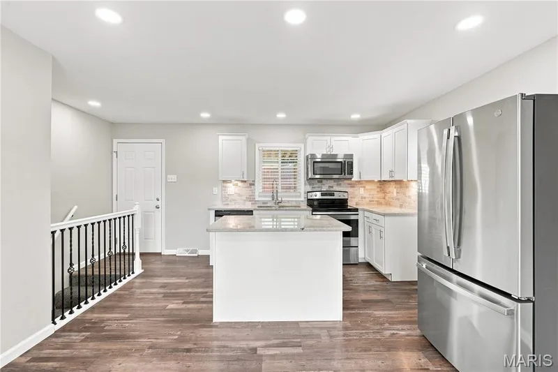Kitchen featuring a central island, white cabinetry, stainless steel appliances, and wood-finish flooring — 1620 Dale Avenue, St Charles, MO 63301