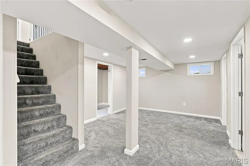 Spacious finished basement featuring polished concrete flooring, recessed lighting, structural support columns, and direct staircase access — 1620 Dale Avenue, St Charles, MO 63301
