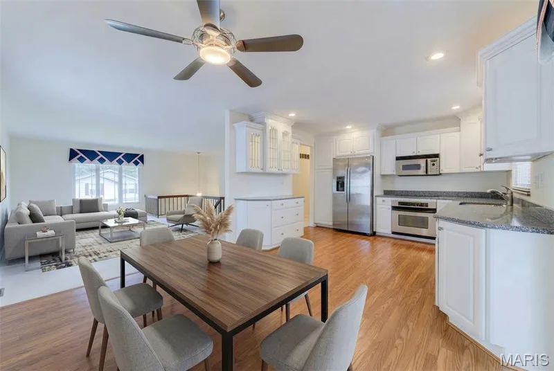 Hardwood-finish flooring in kitchen and dining room.accents. stainless steel appliances, dark stone countertops, and recessed lighting — 127 Spring Leaf Drive, St Peters, MO 63376