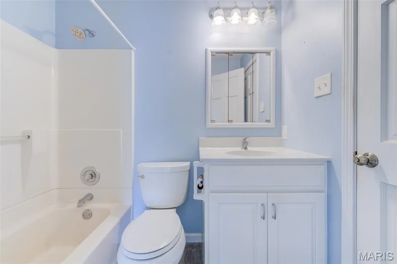Integrated bathtub and shower combination with chrome fixtures, white vanity with an integrated sink, framed mirrored medicine cabinet, and a five-bulb vanity light fixture — 127 Spring Leaf Drive, St Peters, MO 63376