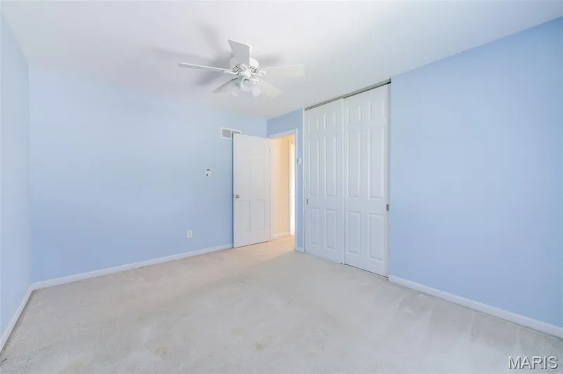 Carpeted flooring, light blue walls, overhead ceiling fan, white paneled doors, and a built-in closet with sliding doors — 127 Spring Leaf Drive, St Peters, MO 63376