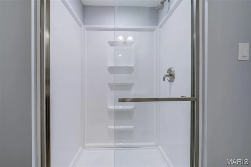 Glass-enclosed shower with brushed nickel fixtures, a built-in shelving system, and a white shower pan — 127 Spring Leaf Drive, St Peters, MO 63376