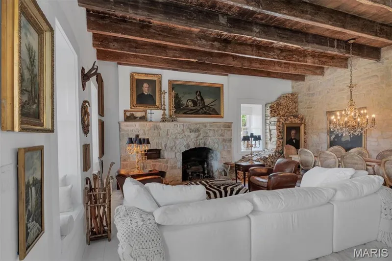 Exposed wood ceiling beams, stone fireplace, stone accent wall, and a crystal chandelier — 2275 Highway F, Defiance, MO 63341