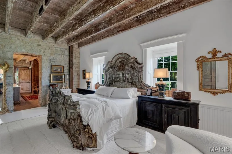 Exposed wood beam ceiling, stone accent wall, arched doorway, two windows with trim, and white walls — 2275 Highway F, Defiance, MO 63341