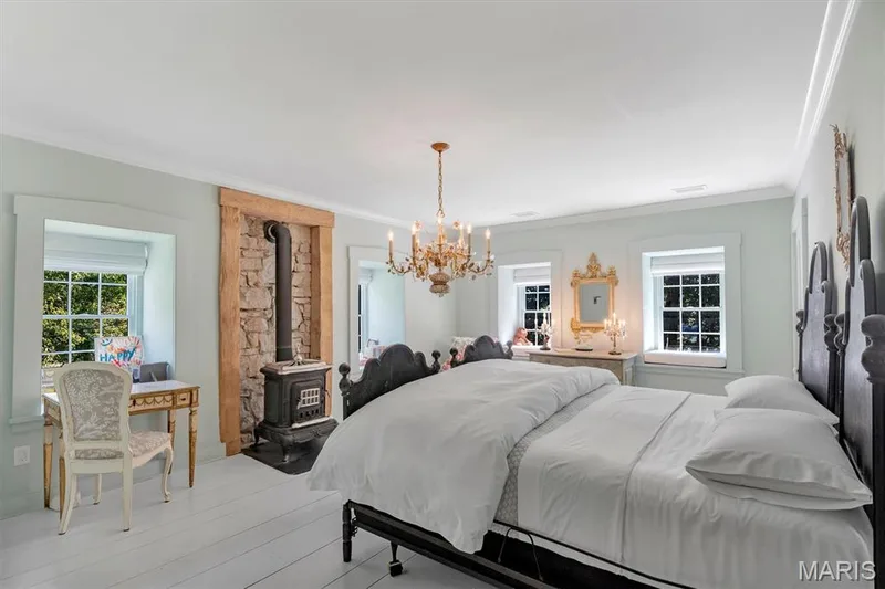 Wood-finish flooring with an antique-style wood-burning stove featuring a stone surround — 2275 Highway F, Defiance, MO 63341
