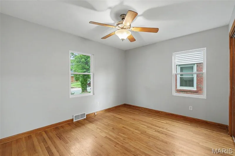 The primary bedroom is also graced with the beautiful hardwood-finished- flooring, neutral wall colors, and a ceiling fan with integrated lighting. — 502 Pine Street, St Charles, MO 63301