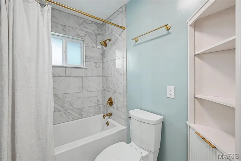 A decorative corner shelving unit with gold accents provides practical storage and a place for decorative touches. — 502 Pine Street, St Charles, MO 63301