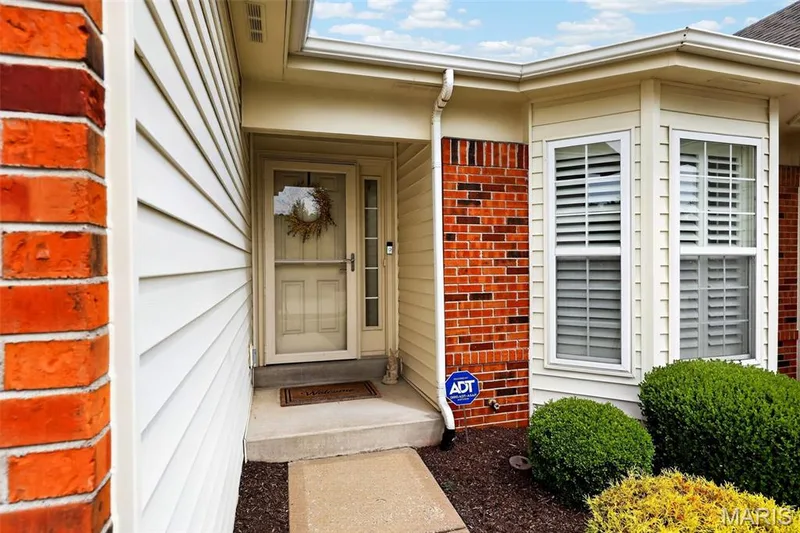 Exterior featuring brick accents, horizontal siding, bay windows with shutters, and a concrete entry path — 14737 Ladue Bluffs Crossing Drive, Chesterfield, MO 63017