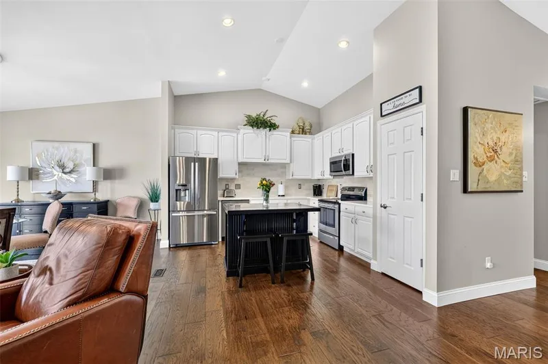 Vaulted ceilings, wood flooring, white cabinetry, stainless steel appliances, and a central kitchen island — 14737 Ladue Bluffs Crossing Drive, Chesterfield, MO 63017
