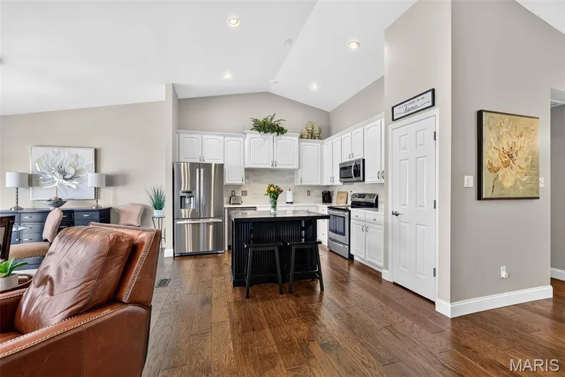 Vaulted ceilings, wood flooring, white cabinetry, stainless steel appliances, and a central island with bar seating — 14737 Ladue Bluffs Crossing Drive, Chesterfield, MO 63017