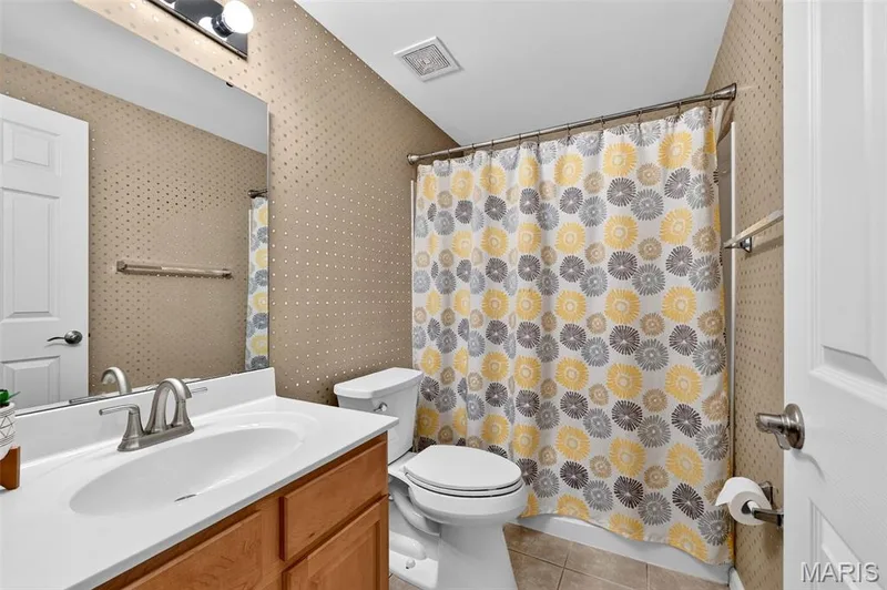 Bathroom with a single vanity, wood-finish cabinetry, a white countertop with an integrated sink, and brushed nickel fixtures — 14737 Ladue Bluffs Crossing Drive, Chesterfield, MO 63017