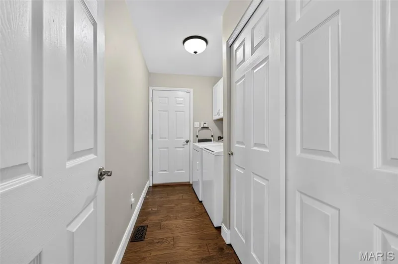 Laundry area featuring wood-finish flooring, white paneled doors, and a flush mount ceiling light — 14737 Ladue Bluffs Crossing Drive, Chesterfield, MO 63017
