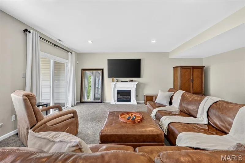 Spacious living area featuring neutral wall tones, recessed lighting, a built-in fireplace, and sliding glass doors — 14737 Ladue Bluffs Crossing Drive, Chesterfield, MO 63017