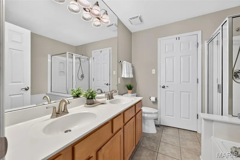 Dual vanity with white undermount sinks, brushed nickel faucets, and wood-finish cabinetry — 14737 Ladue Bluffs Crossing Drive, Chesterfield, MO 63017