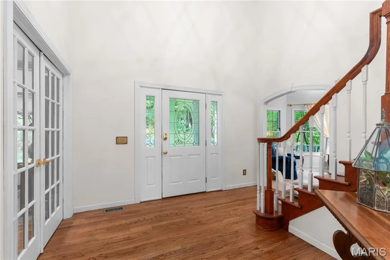 The grand entryway featuring a soaring ceiling, wood flooring, and a custom wood staircase welcomes you home — 19342 Dogwood Valley Court, Wildwood, MO 63038