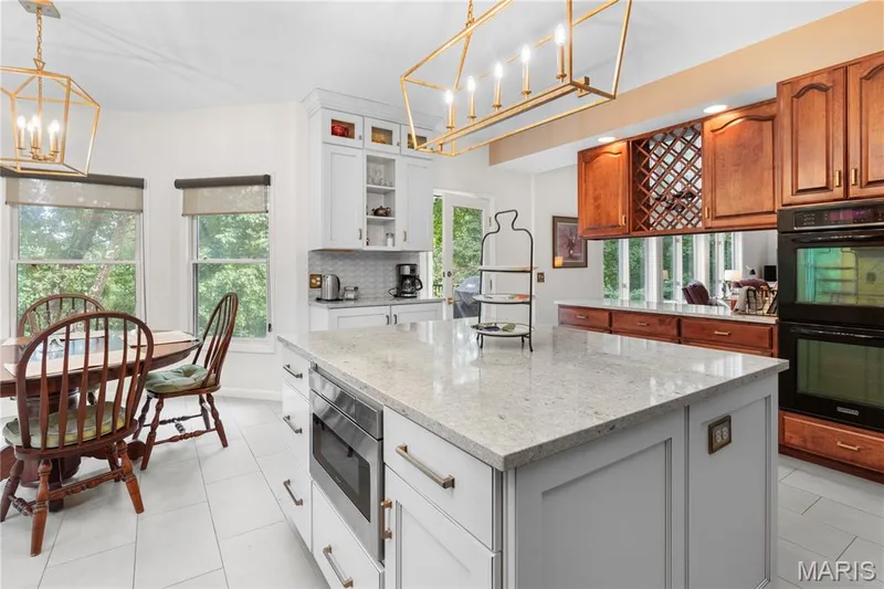 The gourmet kitchen has an oversized  central island with quartz  countertops, built-in microwave, white shaker cabinetry, and loads of storage. A cook's dream! — 19342 Dogwood Valley Court, Wildwood, MO 63038